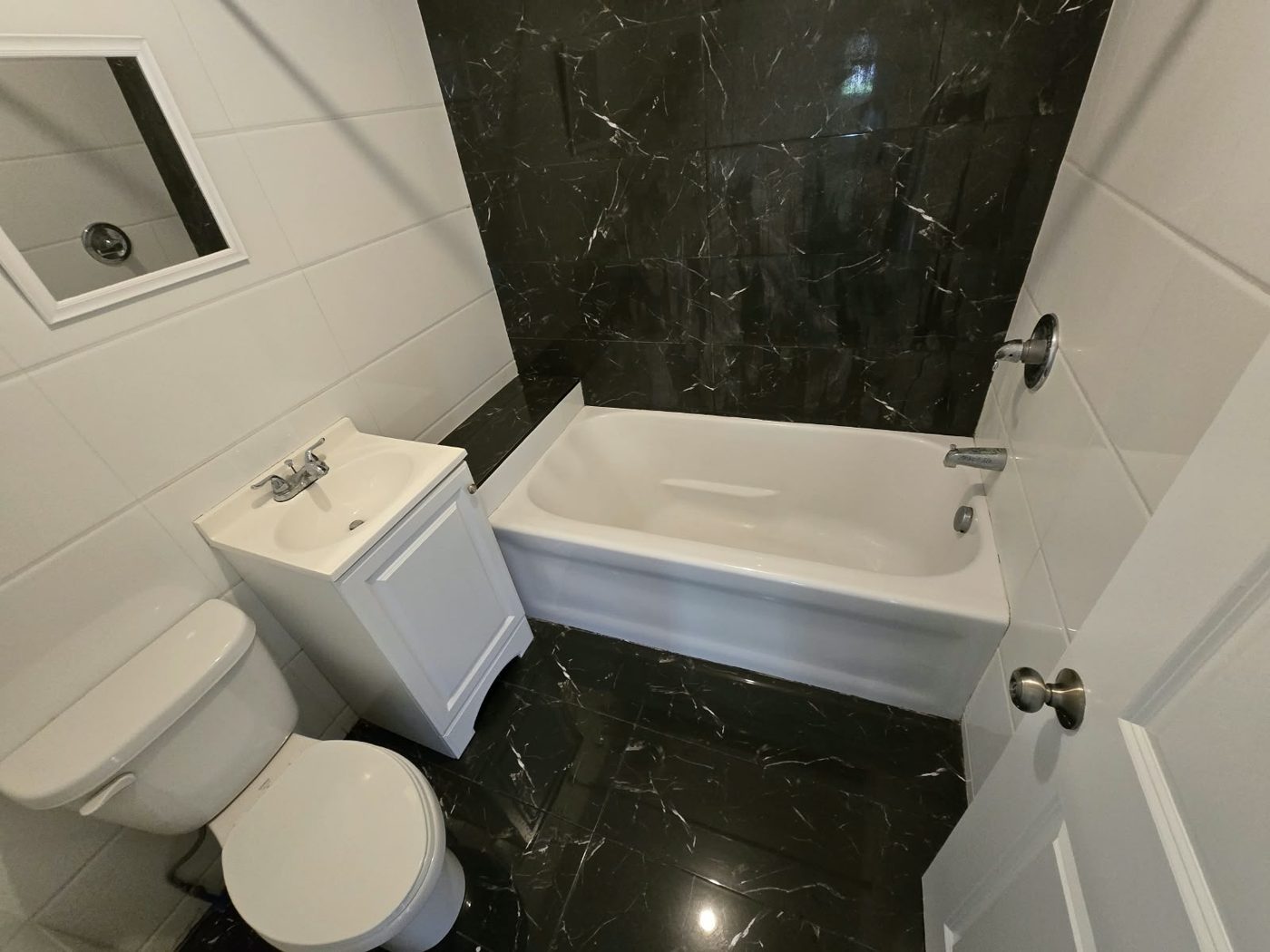 Sparkling bathroom with white tub and sink and polished black marble tile