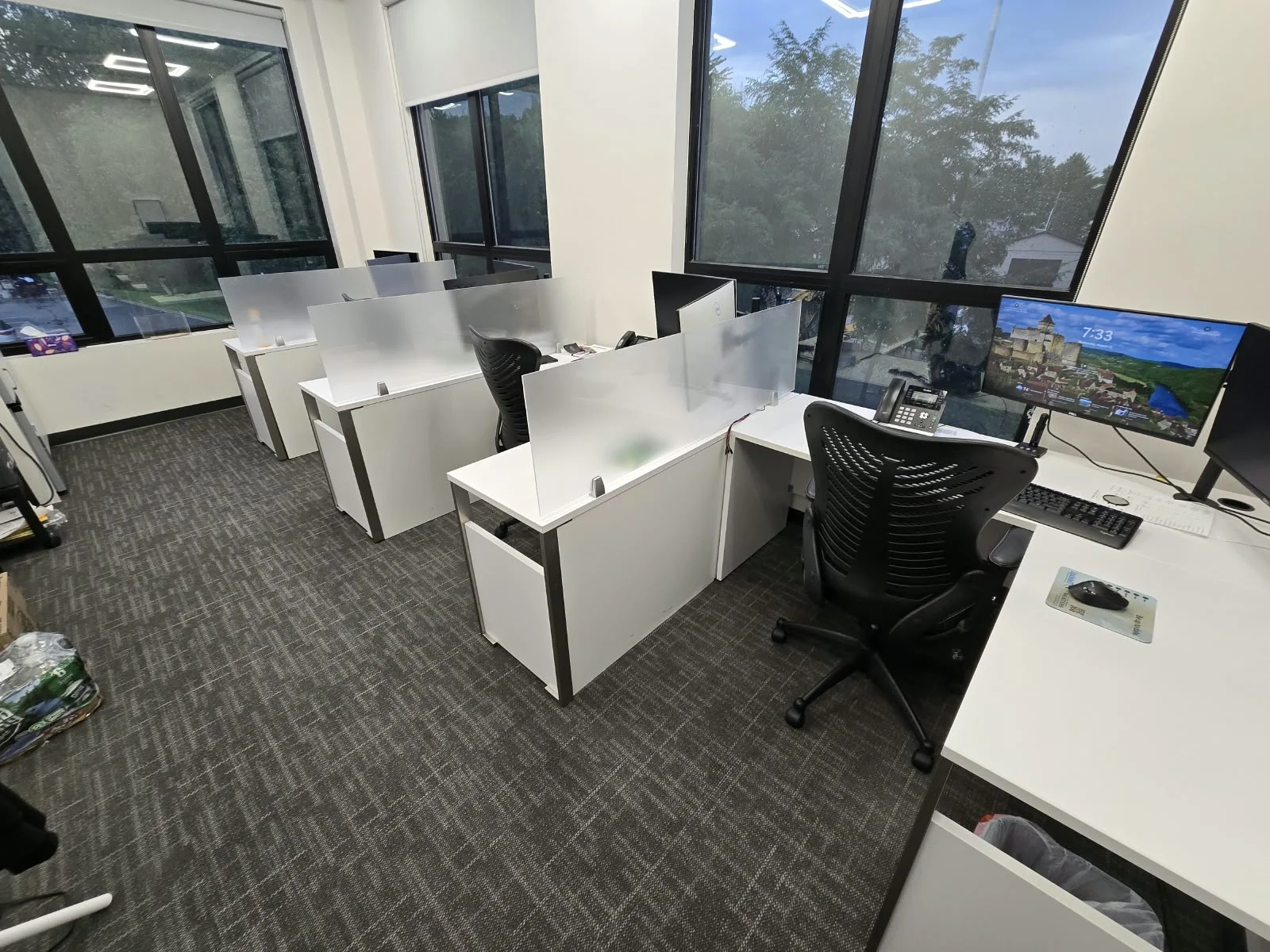 Clean open office with white desks, frosted dividers and freshly vacuumed carpet