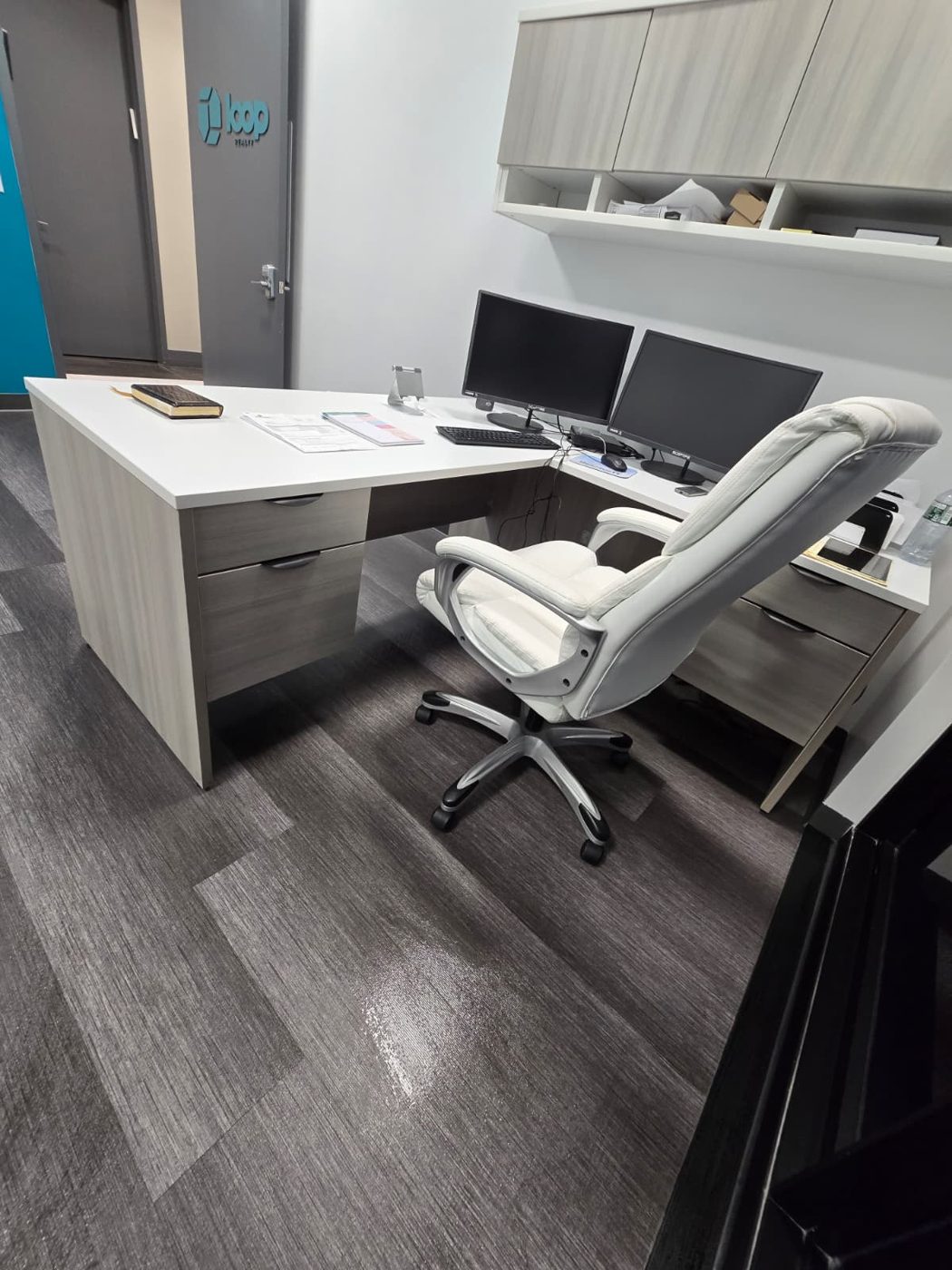 Tidy private office with an L-shaped desk, white chair and spotless floor